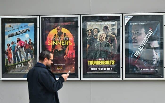 A man walks past movie posters at at AMC Theat