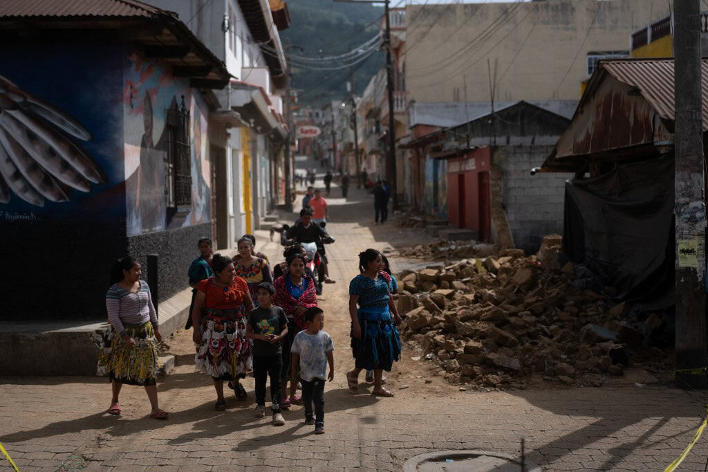 People walk in front of a house destroyed during a series of earthquakes in Santa Maria de Jesus Guatemala
