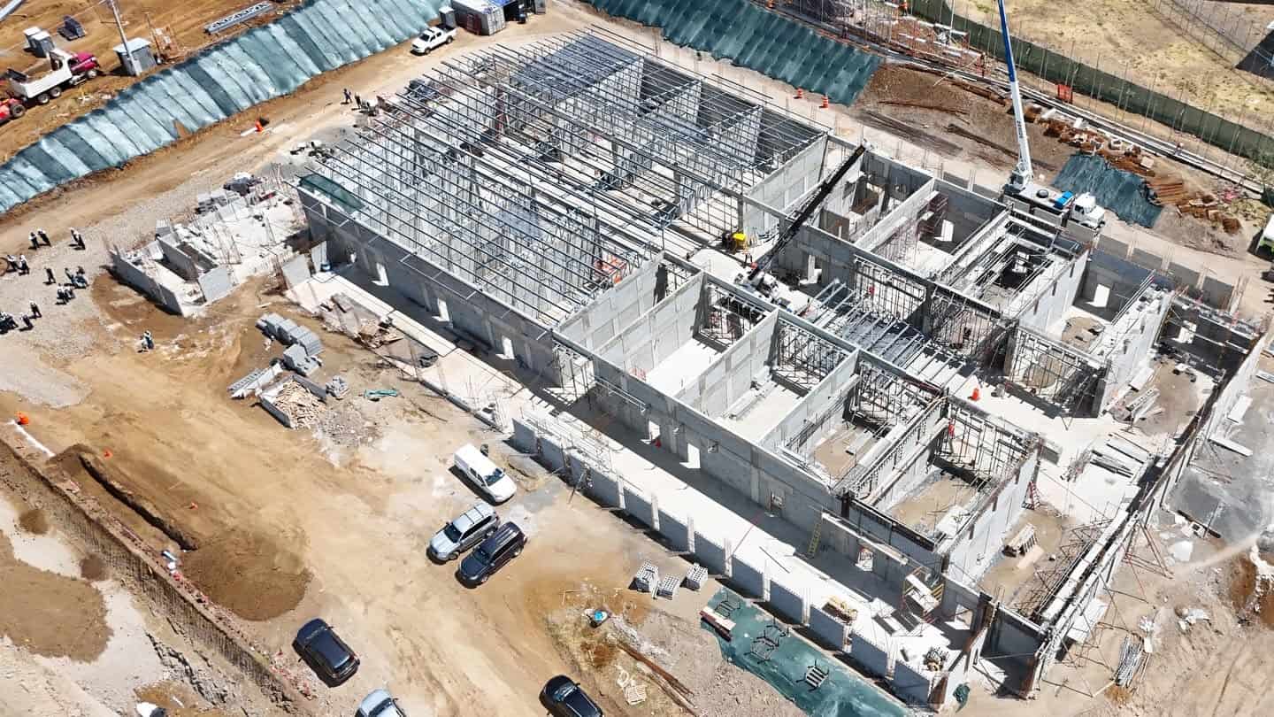 Aerial view of the CACCO high-security prison construction site at the La Reforma prison complex in Alajuela, Costa Rica, with concrete walls, steel framing and construction equipment visible.
