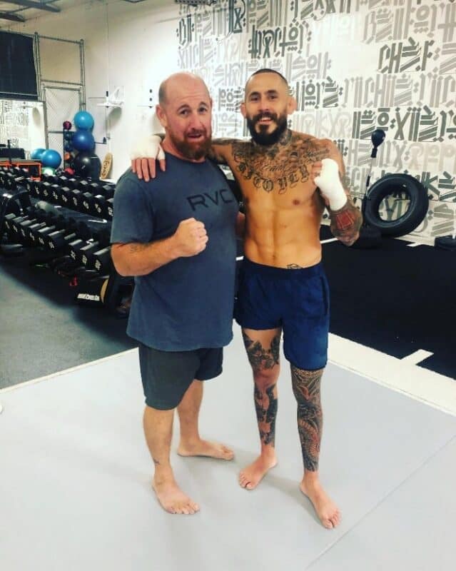 Two athletes pose with boxing gloves in gym, 'ROCKS' banner visible.