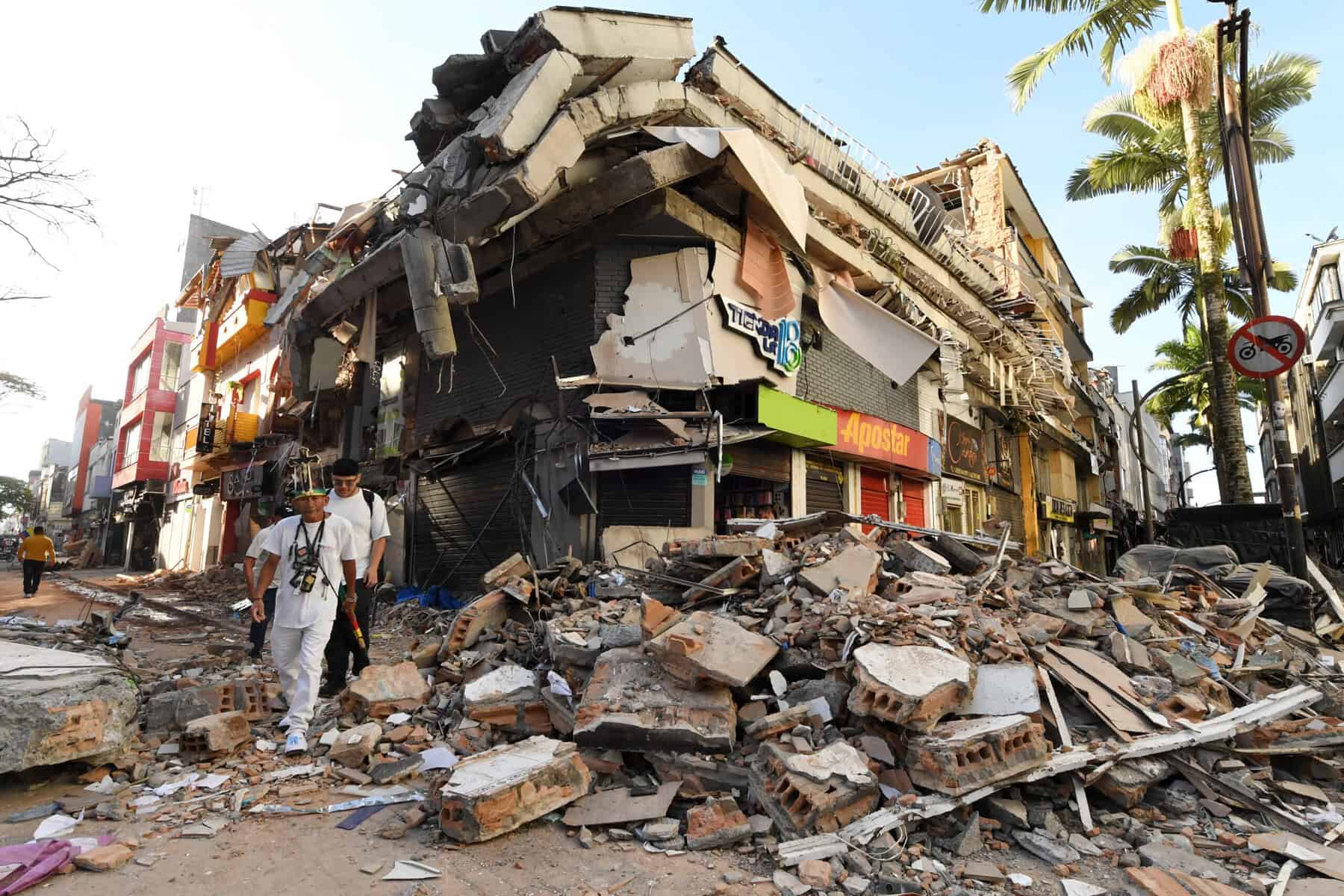 People walk past the rubble of a collapsed building after an earthquake in Pereira, Colombia
